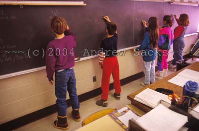Grade school students write on blackboard