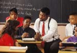 High school teacher helps boy at desk