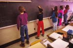 Grade school students write on blackboard